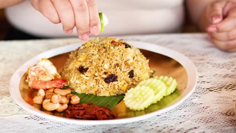 squeezing lime over pineapple baked rice dish