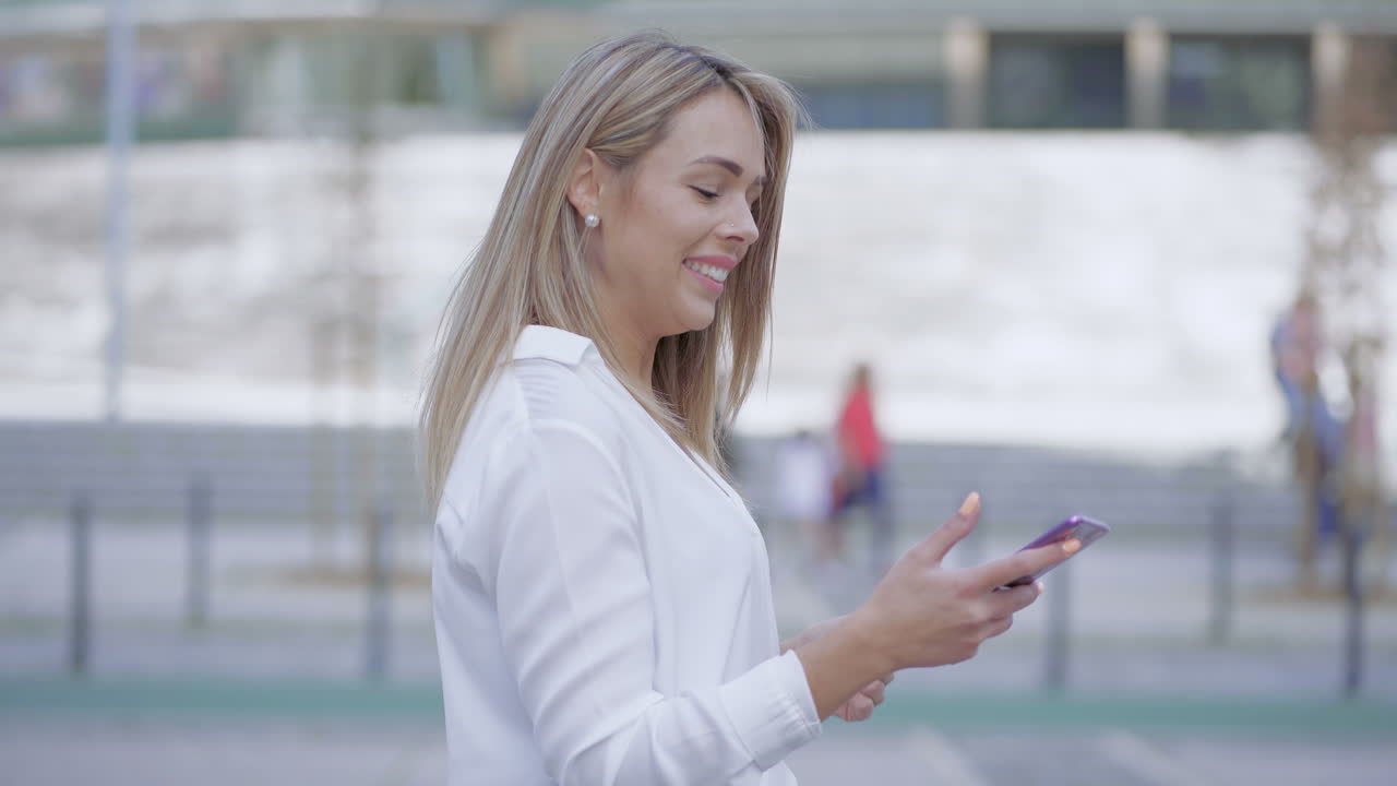 Giovane donna felice che usa lo smartphone all'aperto