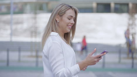 Happy-young-woman-using-smartphone-outdoor