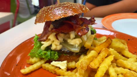 hamburguesa con queso con tocino crujiente, pepinillos, lechuga y papas fritas, experiencia de comida no saludable en un restaurante, tiro de 4k