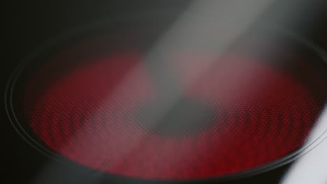 centrándose en un plato rojo brillante caliente o elemento en una estufa de vidrio en una cocina listo para cocinar la cena en una vista de cerca