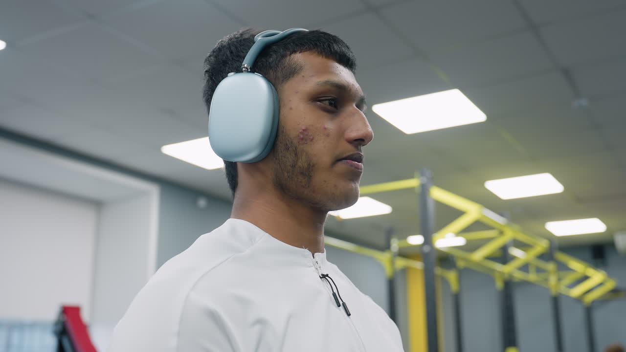 Close up of student lifting barbell loaded with weight plate in well lit gym, showing hands gripping chrome collar on rubber flooring during intense strength exercise