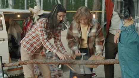 young tourists cooking food over campfire