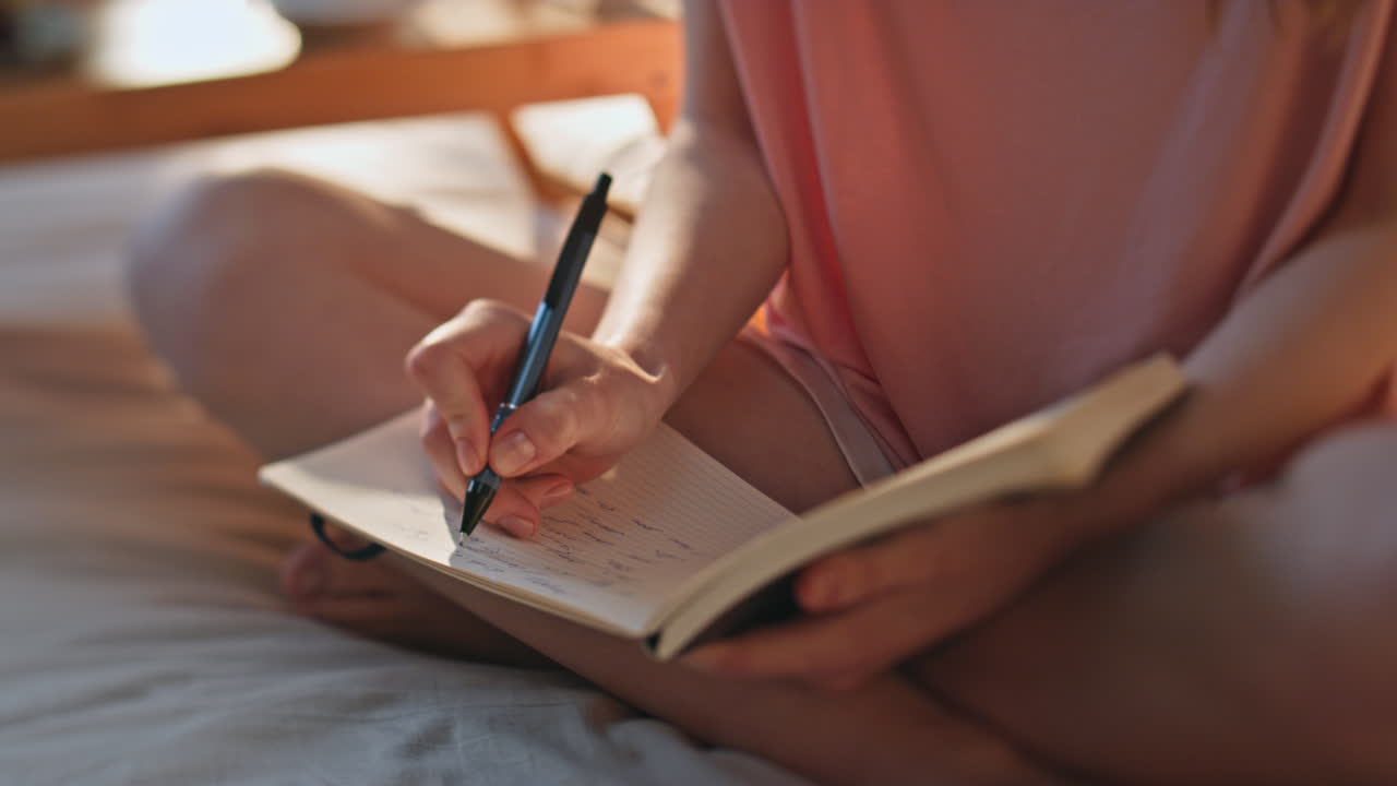 Teenage girl writing diary in sunlight closeup. Hands holding pen noting in book