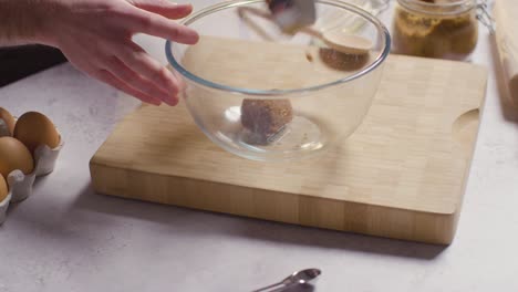 close up of man in kitchen at home adding ingredients to bowl to bake cake 2