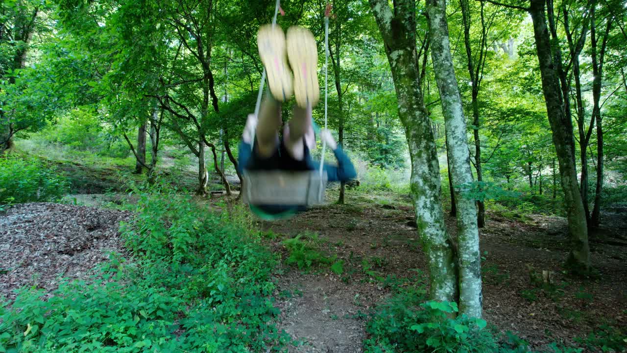 파란 머리와 노란 신발을 신고 숲에서 거대한 그네를 타는 젊은 성인