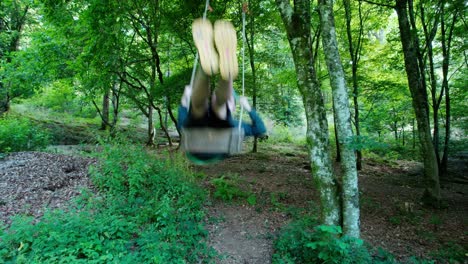 young adult swinging on giant swing in forest with blue hair en yellow shoes