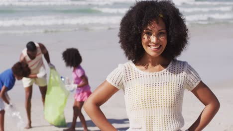 Portrait-of-african-american-mother,-her-family-collecting-rubbish-and-bottles-from-the-beach