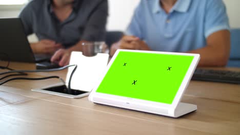 un ipad mostrando una página verde durante una reunión corporativa en una sala de juntas