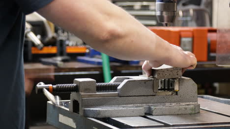 prensa de perforación práctica en la mesa de la fábrica de taller mientras un técnico de precisión ingeniero mecánico perfora el agujero