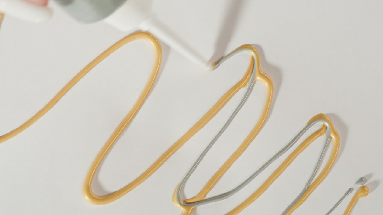 Primo Piano di Mano che Spreme Vernice Oro e Argento da un Tubetto