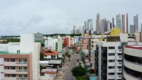 Dolly-in-rising-aerial-drone-shot-of-the-colorful-tropical-beach-capital-city-of-Joao-Pessoa-in-Paraiba,-Brazil-from-the-Tambaú-neighborhood-on-an-overcast-morning