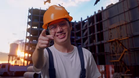 un trabajador asiático tocando su pecho y luego señalándote en el sitio de construcción.