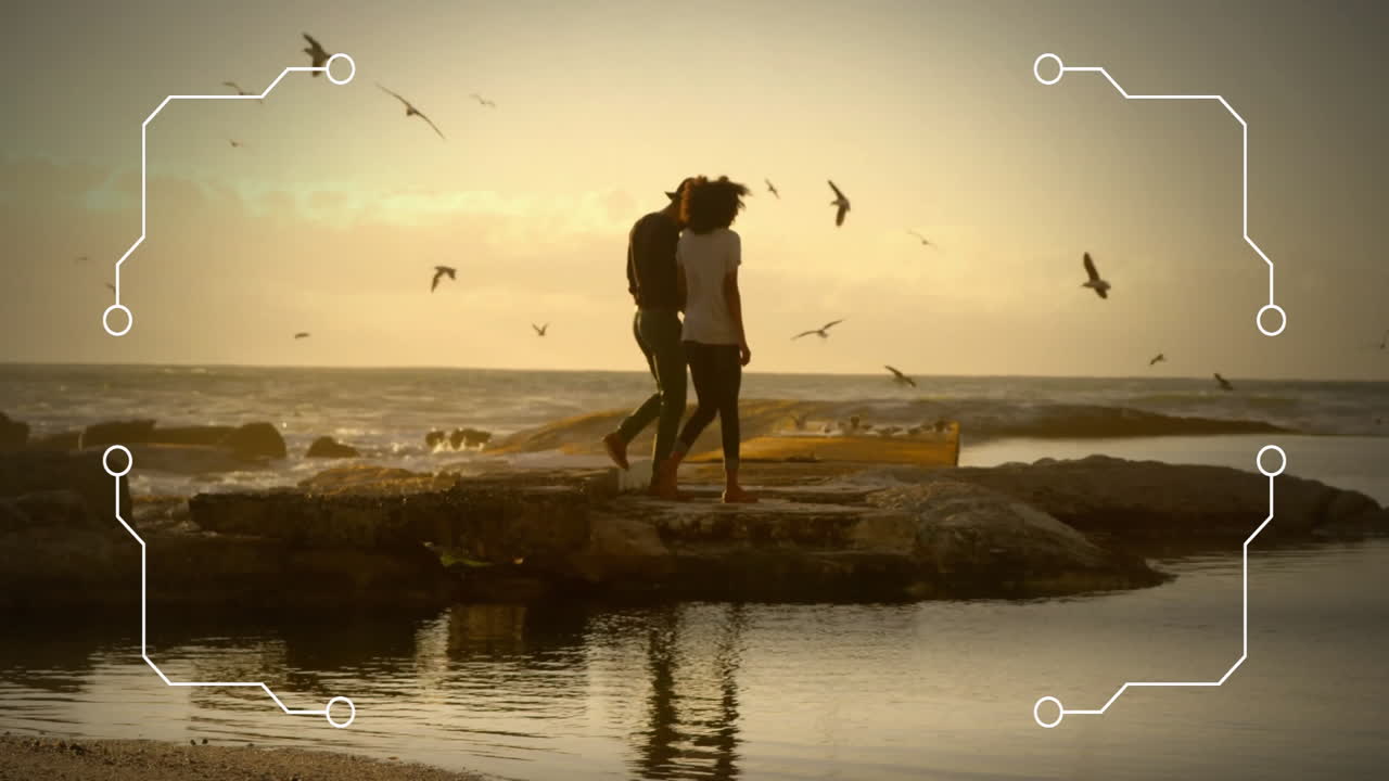 Animation of white frame over biracial couple walking at beach