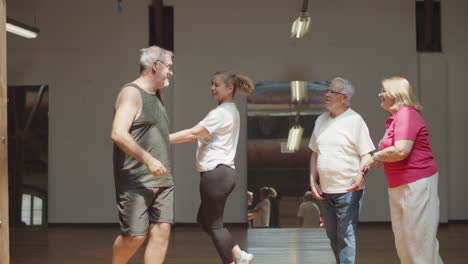 Long-shot-of-happy-senior-men-and-women-dancing-in-ballroom