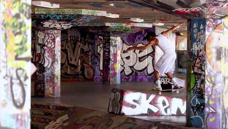 skateboarder performing trick in graffiti-covered tunnel