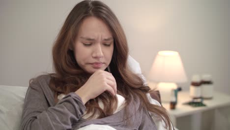 sick woman sneezing in tissue in bed at evening. sick girl blowing nose