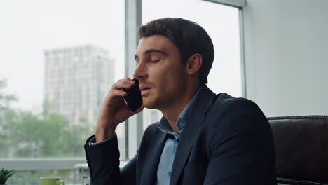 Closeup-focused-employee-talking-cellphone-in-office.-Confident-manager-working