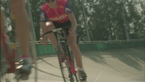 a group of cyclists ride around a curved track