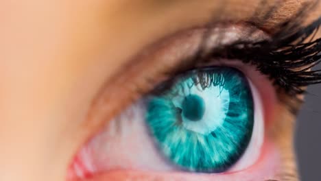 Close-up-of-female-green-eye-against-grey-background