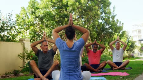 Trainer-and-seniors-performing-yoga-in-garden-4k