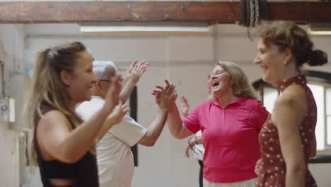 People-standing-against-each-other-in-ballroom-and-giving-five