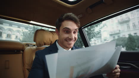hombre de negocios feliz buscando datos en un coche de negocios. hombre satisfecho en un coche de lujo