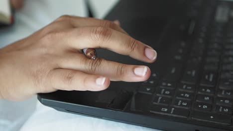 close-up of a hand typing on a laptop keyboard