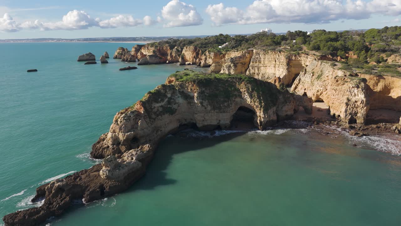 Vista aérea de Ponta João de Arens en Portimão, Portugal, con impresionantes acantilados costeros, aguas turquesas y grutas marinas