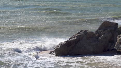 mar agitado con olas golpeando las rocas en la playa al mediodía