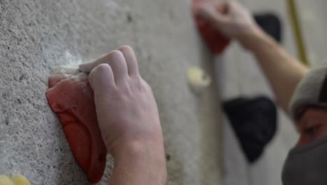 rock climber climbing an indoor rock wall using athletic chalk for grip.