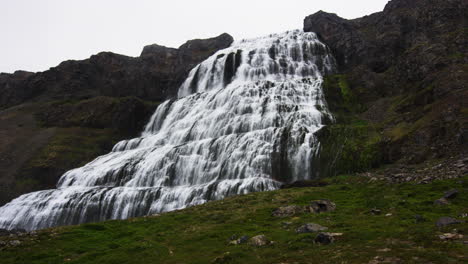 wide and massive waterfall on tall mountain in low angle zoom in view