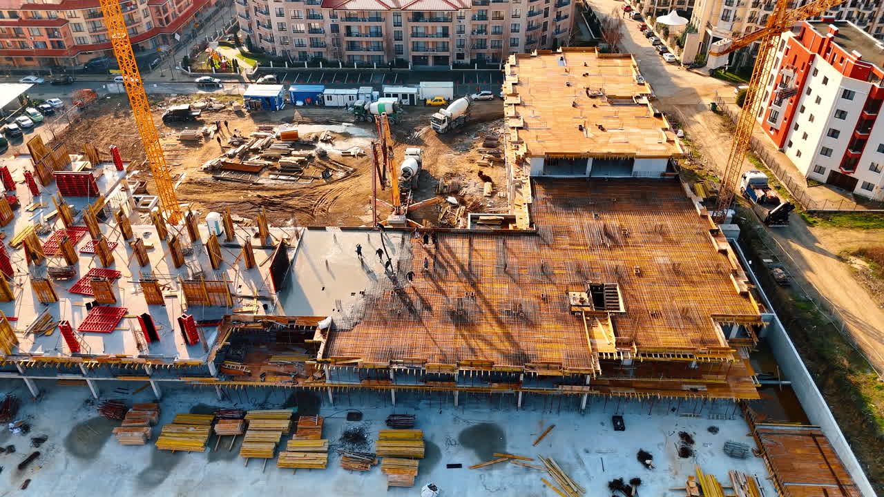 Aerial shot of concrete pouring process on building site. View of concrete mixer trucks and pumps at construction site