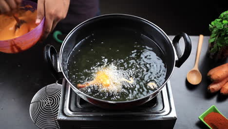 hot oil in a cooking pan, chef frying the pieces of chicken lollipop in this hot oil for preparing spicy non vegetarian indian food