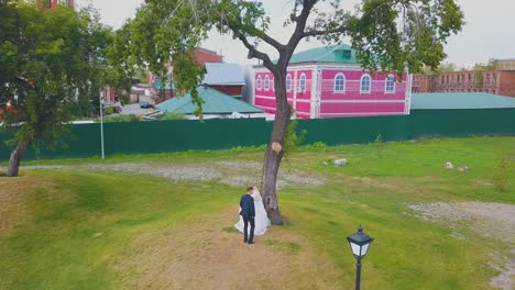 happy couple dances near tree at christian church aerial