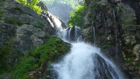 sunrise on high mountains of albanian alps, waterfall scenery with rocky slope and green trees