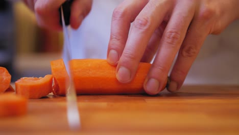 the cook cuts a carrot on a wooden board