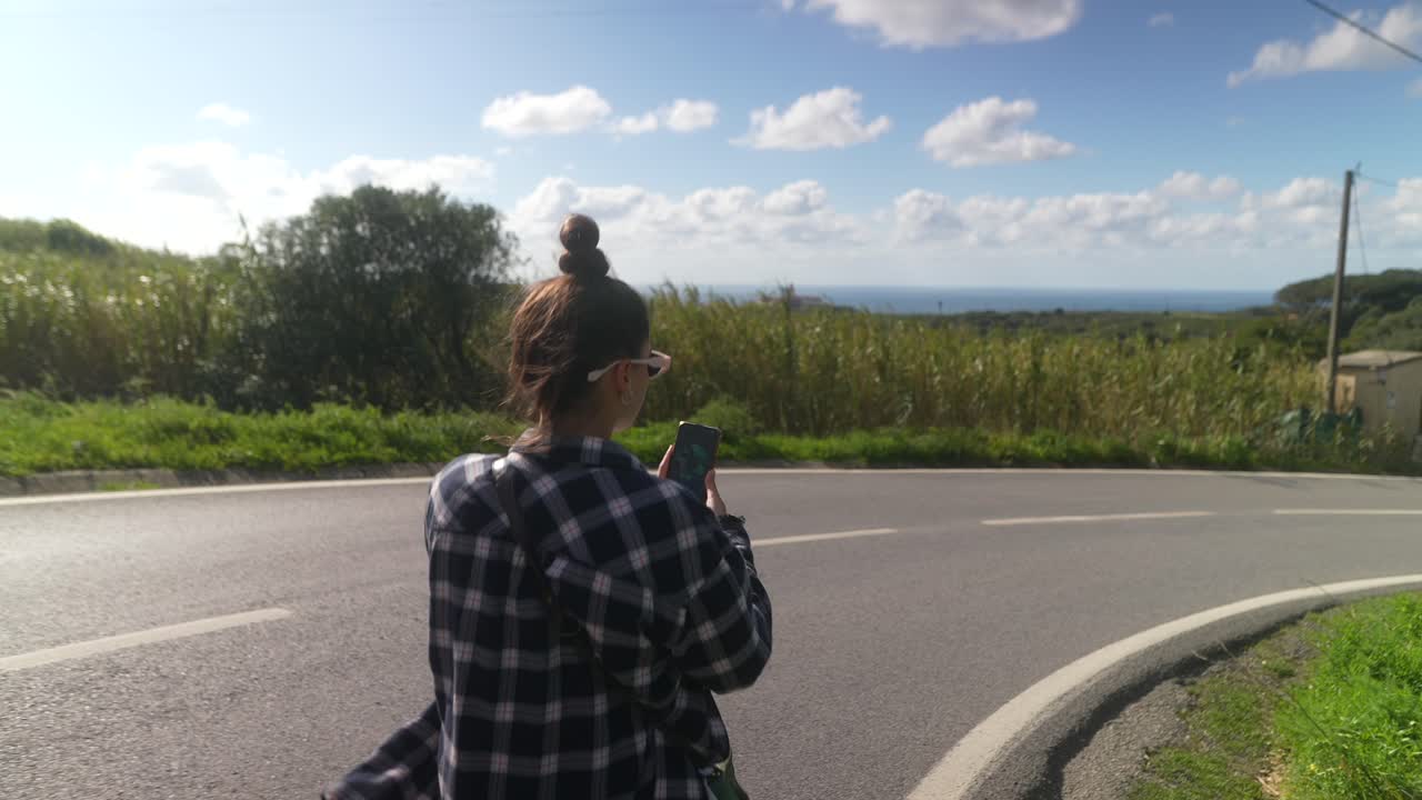 Woman taking photo on a scenic road