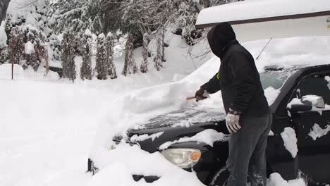 man cleaning snow off car window in canada