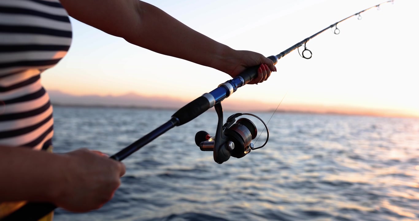 Una persona al tramonto pesca con una canna da pesca