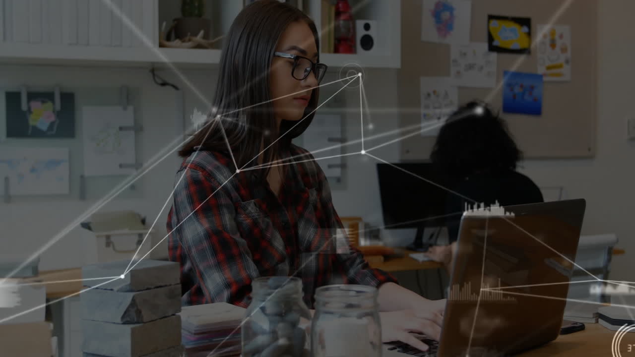 Designer typing on laptop in creative tech office, showing animated charts around fabric swatches