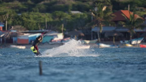 Kiteboarder-leans-to-build-momentum-skipping-along-ocean-with-tropical-beach-background-gaining-air