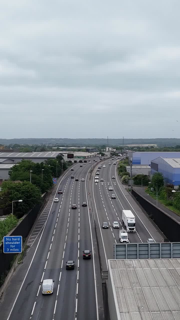 Portrait drone rising over M25 in Hertfordshire, showing tunnel and warehouses