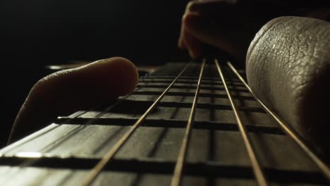 macro close up, musician fingerstyle plucking guitar strings in dark studio