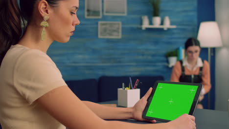 freelancer leyendo un libro en línea usando una tableta con una pantalla verde simulada