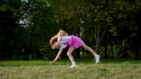 little girl having fun on the green grass while making an acrobatic wheel. young sporty kid has a really good mood.