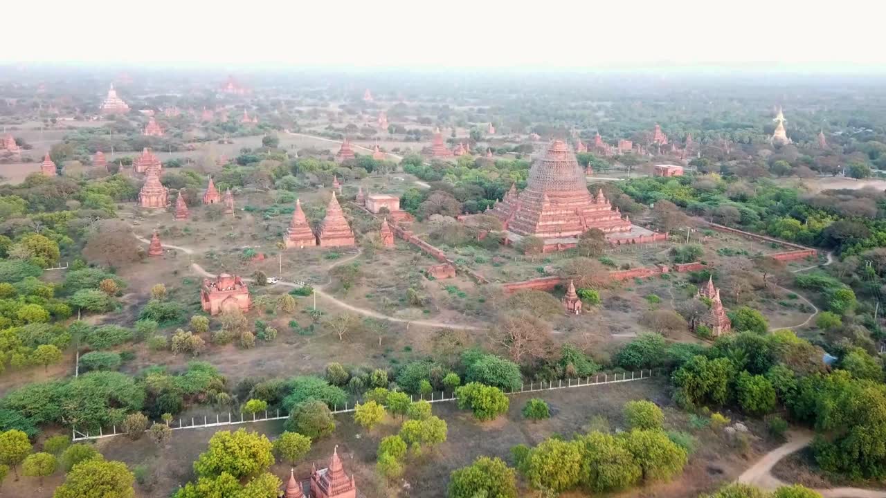 A panoramic view of Bagan, Myanmar, featuring ancient temples and pagodas spread across the lush landscape. The historic site, rich in cultural heritage, is bathed in soft light amidst greenery