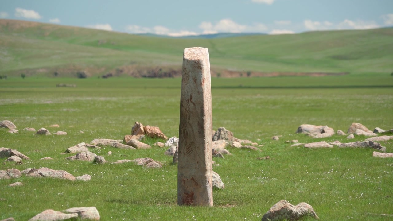 Antica stele di pietra che si erge in un vasto prato verde