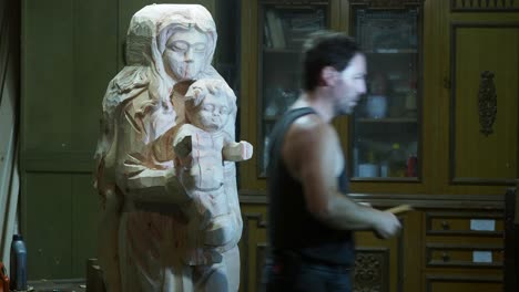 artisan carefully carves the wooden madonna and child statue inside a workshop, shaping sacred details with precision and devotion in traditional craftsmanship
