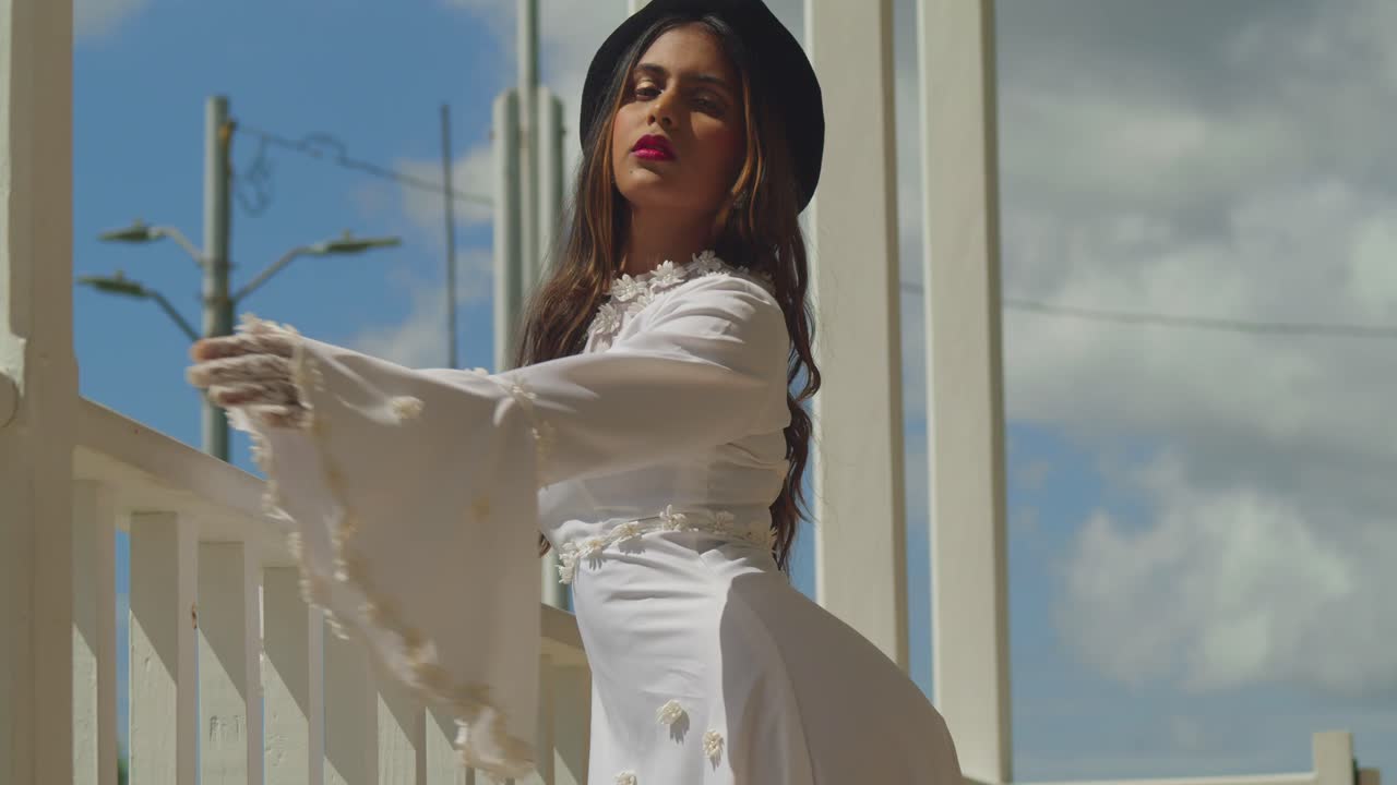 A young girl wearing a vintage wedding gown, standing atop an ancient fort.